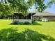 A screened-in porch is situated in a backyard near a brick home, shrubs, and chairs at 1008 Whispering Trl, Greenfield, IN 46140