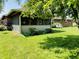Landscaped yard with charming screened-in porch with white chairs on the patio at 1008 Whispering Trl, Greenfield, IN 46140