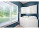 Well-lit laundry room with white washer and dryer, overhead cabinets, and large window at 1031 Lancashire Ln, Pendleton, IN 46064