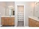 Bathroom featuring double sinks, lighted mirrors, wood cabinets and walk-in closet at 10668 Whippoorwill Ln, Indianapolis, IN 46231