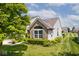 Side view of the home showcasing manicured landscaping, large window, and lush green lawn at 10668 Whippoorwill Ln, Indianapolis, IN 46231