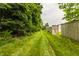 Large backyard with lawn and mature trees, featuring a wooden gate, offering privacy and natural beauty at 1112 Halifax Ct, Indianapolis, IN 46231