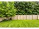 A spacious backyard featuring a lush lawn, tall trees, and a wood fence, providing privacy at 1112 Halifax Ct, Indianapolis, IN 46231