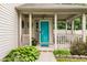 Inviting front porch featuring a vibrant turquoise door, classic columns, and decorative greenery at 1112 Halifax Ct, Indianapolis, IN 46231