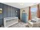 Stylish Bedroom features a white crib, accent wall, modern lighting and an inviting chair by the window at 12259 Sweet Creek Trl, Fishers, IN 46037
