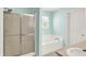 This bathroom features a shower, a tub, blue walls, and a window with green tree outside and an entrance door at 12322 Cool Winds W Way, Fishers, IN 46037