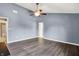 This bedroom features wood floors, light blue walls, a brown ceiling fan and an ensuite bathroom at 12322 Cool Winds W Way, Fishers, IN 46037