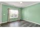 A bright bedroom featuring mint walls, wood-look flooring, a large window with curtains, and neutral trim at 12322 Cool Winds W Way, Fishers, IN 46037