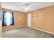 This bedroom features neutral carpet, orange walls, a white ceiling fan and a window with blue curtains at 12322 Cool Winds W Way, Fishers, IN 46037