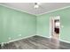 Bedroom with mint walls, wood-look flooring, neutral trim and a doorway that leads into a kitchen area at 12322 Cool Winds W Way, Fishers, IN 46037