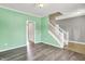 Living room showcasing gray and mint walls, wood-look and tile flooring, with an adjacent staircase and doorway at 12322 Cool Winds W Way, Fishers, IN 46037