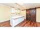 Basement kitchen featuring modern island, white cabinets and unique sliding wooden doors at 14109 Secretariat Ct, Carmel, IN 46074