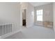 Bright bedroom featuring neutral walls, plush carpeting, and a window offering natural light and a glimpse into the ensuite bathroom at 14234 Community Dr, Carmel, IN 46033