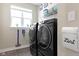 Well-lit laundry room features modern black washer and dryer, convenient storage shelves, and stylish decor for efficient chores at 14234 Community Dr, Carmel, IN 46033