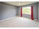 Spacious carpeted bedroom featuring a ceiling fan and window with red curtains for a cozy retreat at 14492 Cotswold Ln, Carmel, IN 46033