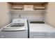 This laundry room features a front-loading washing machine, a dryer, and built-in shelving for ample storage at 14492 Cotswold Ln, Carmel, IN 46033