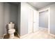 Bright half bathroom featuring gray walls, ceramic tiled floor, toilet, and white closet doors at 196 Park Ave, Bargersville, IN 46106