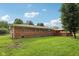 Spacious backyard featuring a well-kept lawn, a brick home, mature trees, and a cozy wooden deck at 230 Love Ave, Greenwood, IN 46142