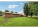 A generously sized backyard features lush green grass, a brick home, mature trees, and a charming wooden deck at 230 Love Ave, Greenwood, IN 46142