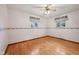 Bright bedroom featuring hardwood floors, a ceiling fan, and two windows with floral valances at 230 Love Ave, Greenwood, IN 46142