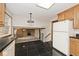 Kitchen showcasing wooden cabinets, black tile floor, and open view to living room with brick fireplace at 3545 Whippoorwill Lake N Dr, Monrovia, IN 46157