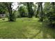 Large lot features green grass with mature trees and a fire pit at 3616 N Dearborn St, Indianapolis, IN 46218