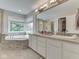 Bright bathroom showcasing a soaking tub, double vanity, and large window with a backyard view at 4084 Mountbatton Dr, Greenwood, IN 46143