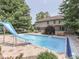 Backyard pool and spa with a slide, surrounded by mature trees and patio area at 4084 Mountbatton Dr, Greenwood, IN 46143