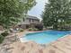 Lush backyard with a sparkling pool, surrounded by mature trees and a spacious patio at 4084 Mountbatton Dr, Greenwood, IN 46143