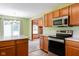 Functional kitchen featuring wood cabinetry, stainless steel appliances, and an open view to the living room at 413 Blue Spring Dr, Indianapolis, IN 46239