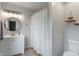 Bright bathroom with a white vanity, round mirror, modern lighting, and a striped shower curtain at 4155 Rolling Trails Rd, Greenwood, IN 46142