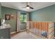 Cozy bedroom featuring warm green walls, a large window view, and a modern baby crib at 4155 Rolling Trails Rd, Greenwood, IN 46142