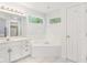 Bright bathroom with white cabinets, marble countertop, tub under the window, and a door at 430 Oakbrook Dr, Columbus, IN 47201