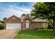 Charming brick home with a well-manicured lawn, an arched entryway, and an attached two-car garage at 5032 Monticello Dr, Columbus, IN 47203