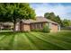 Charming brick home with well-maintained lawn and mature trees in the front yard at 5032 Monticello Dr, Columbus, IN 47203
