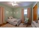 Charming bedroom with a white bed, pastel green walls, and decorative floral accents at 5609 Meadowood Dr, Indianapolis, IN 46224