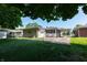 Rear exterior view showing a well-kept lawn, connecting carport and sunroom. Brick and stone accents enhance its charm at 5609 Meadowood Dr, Indianapolis, IN 46224