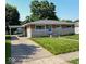 Charming ranch-style home featuring a brick and stone facade, a carport, and a well-manicured lawn at 5609 Meadowood Dr, Indianapolis, IN 46224