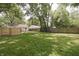 Spacious backyard featuring a wooden fence, mature trees, and a cozy fire pit at 5636 Crittenden Ave, Indianapolis, IN 46220