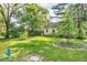 Well-maintained front yard featuring a lush green lawn, mature trees, and colorful landscaping around the house at 6235 N Temple Ave, Indianapolis, IN 46220