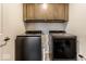 Laundry room with gray front load washer and dryer units, as well as brown overhead cabinets, offering storage and convenience at 628 Tess Blvd, Westfield, IN 46074