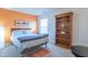 Bright bedroom featuring an orange accent wall, a wooden bookcase, and a comfortable bed at 6480 E Coal Bluff Ct, Camby, IN 46113