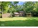 Expansive backyard featuring a charming stone and wood home, a large deck, and a spacious lawn surrounded by trees at 6975 Milhouse Rd, Indianapolis, IN 46221
