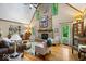 Airy living room with hardwood floors, vaulted ceilings, a stone fireplace, and large windows for natural light at 6975 Milhouse Rd, Indianapolis, IN 46221