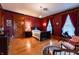Elegant bedroom with hardwood floors, red walls, and natural light at 825 E Washington St, Muncie, IN 47305