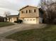 Side view of split-level home with beige siding, showcasing a two-car garage and concrete driveway at 9016 Neptune Dr, Indianapolis, IN 46229