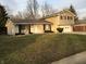 Split-level home with a two-car garage, tan siding, and brick accents on a grassy lot at 9016 Neptune Dr, Indianapolis, IN 46229
