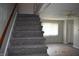 Carpeted staircase leading to a living space with hardwood floors and a ceiling fan at 9016 Neptune Dr, Indianapolis, IN 46229