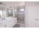 Bathroom with double sinks, white cabinets, a large mirror and a tiled shower with glass doors at 9248 Hawley Dr, Indianapolis, IN 46216