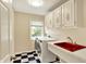 Bright laundry room with checkered floors, red sink, washer and dryer, and white cabinets for storage at 9650 Copley Dr, Carmel, IN 46290